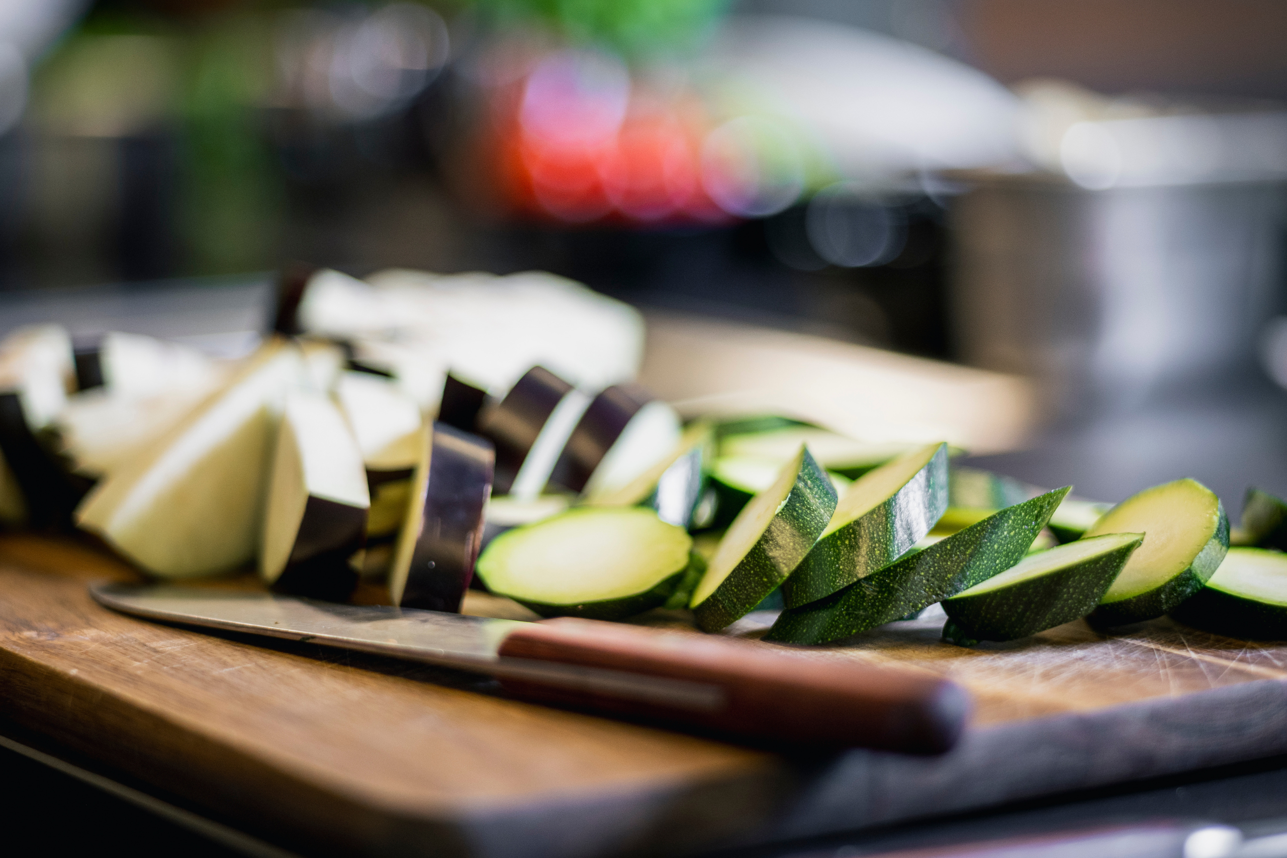 Bild zeigt ein Holzbrett mit geschnittener Zucchiniund edlem Messer darauf, als Einladung für die After Work Kocherlebnissen bei Savoro