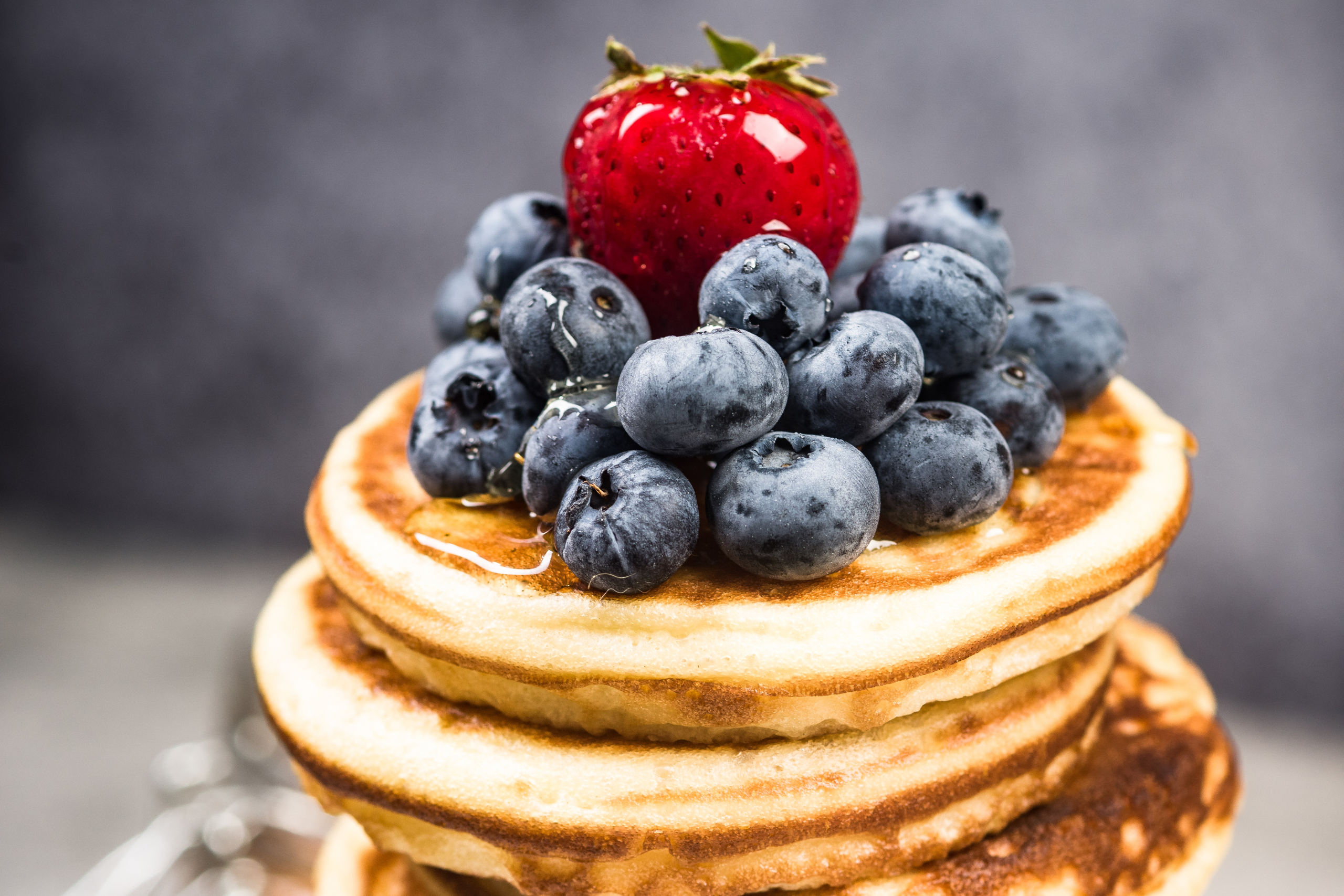 Bild zeigt einen Turm aus Pancakes mit frischen Blaubeeren und einer leckeren Erdbeere drauf, als visuelles Highlight für den Frühstücksbrunch bei Savoro